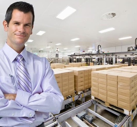 Man standing in a warehouse with stacks of boxes on a conveyor belt